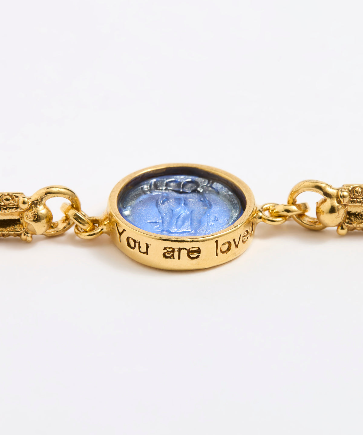Close up Gold link bracelet with round pendant in the centre with blue glass 