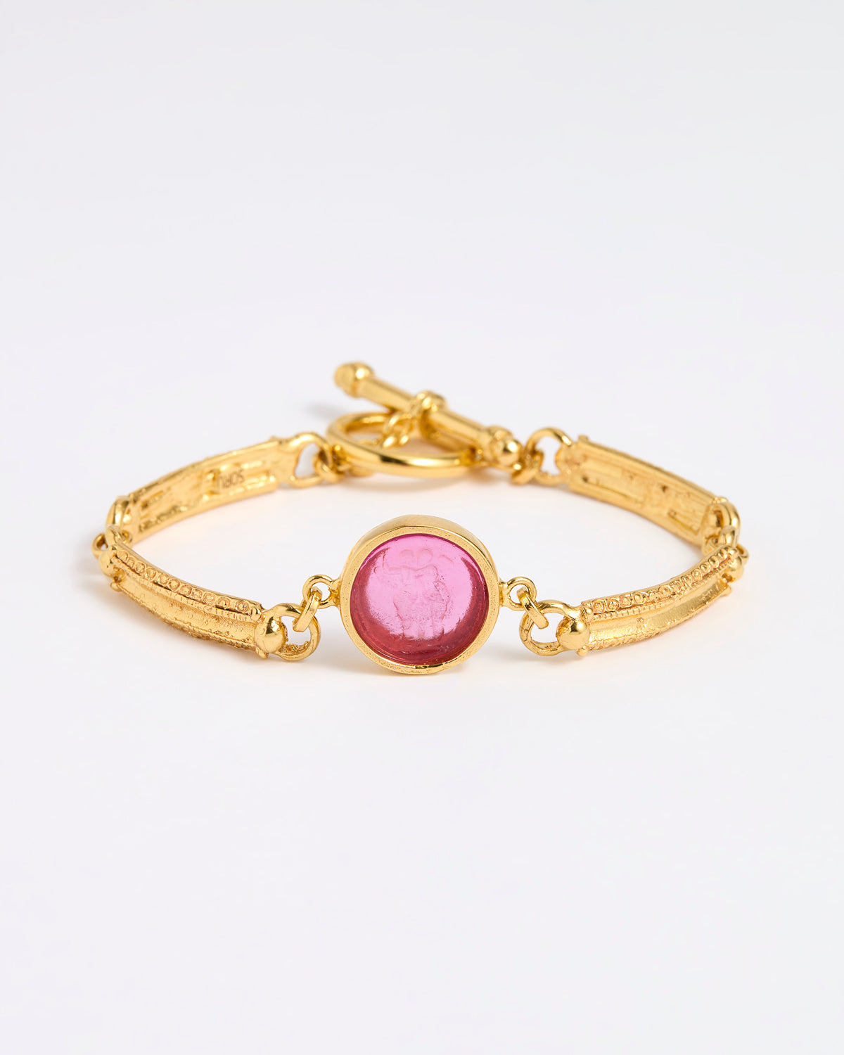 Gold link bracelet with round pendant in the centre with magenta glass