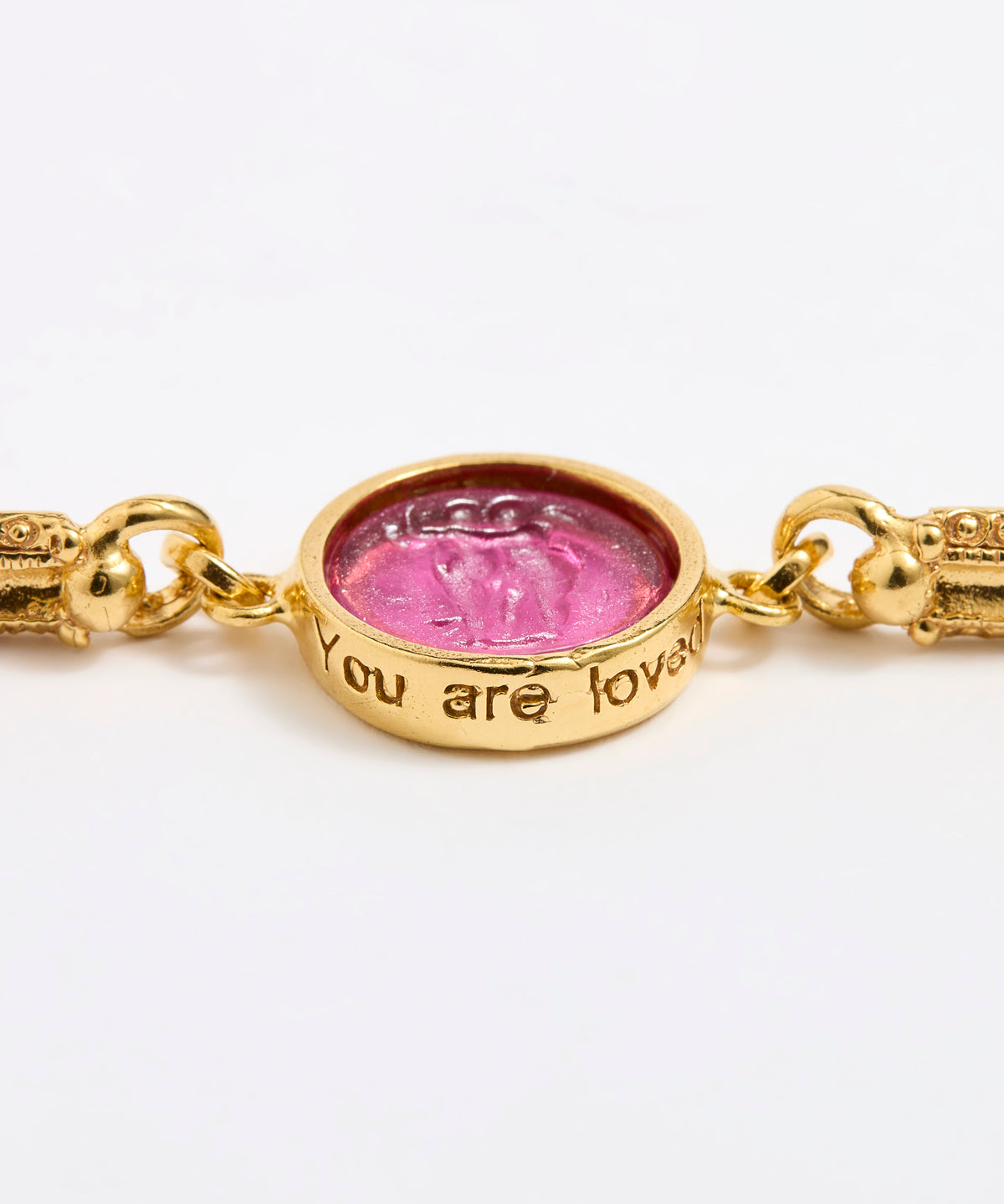 Gold link bracelet with round pendant in the centre with magenta glass and isciption 'you are loved' 