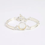 Silver link bracelet with round pendant in the centre with clear glass and embossed image of twins.