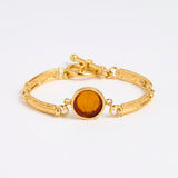 Gold link bracelet with round pendant in the centre with topaz glass
