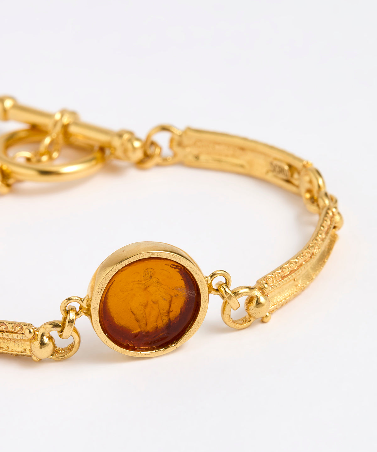 Close up of Gold link bracelet with round pendant in the centre with topaz glass