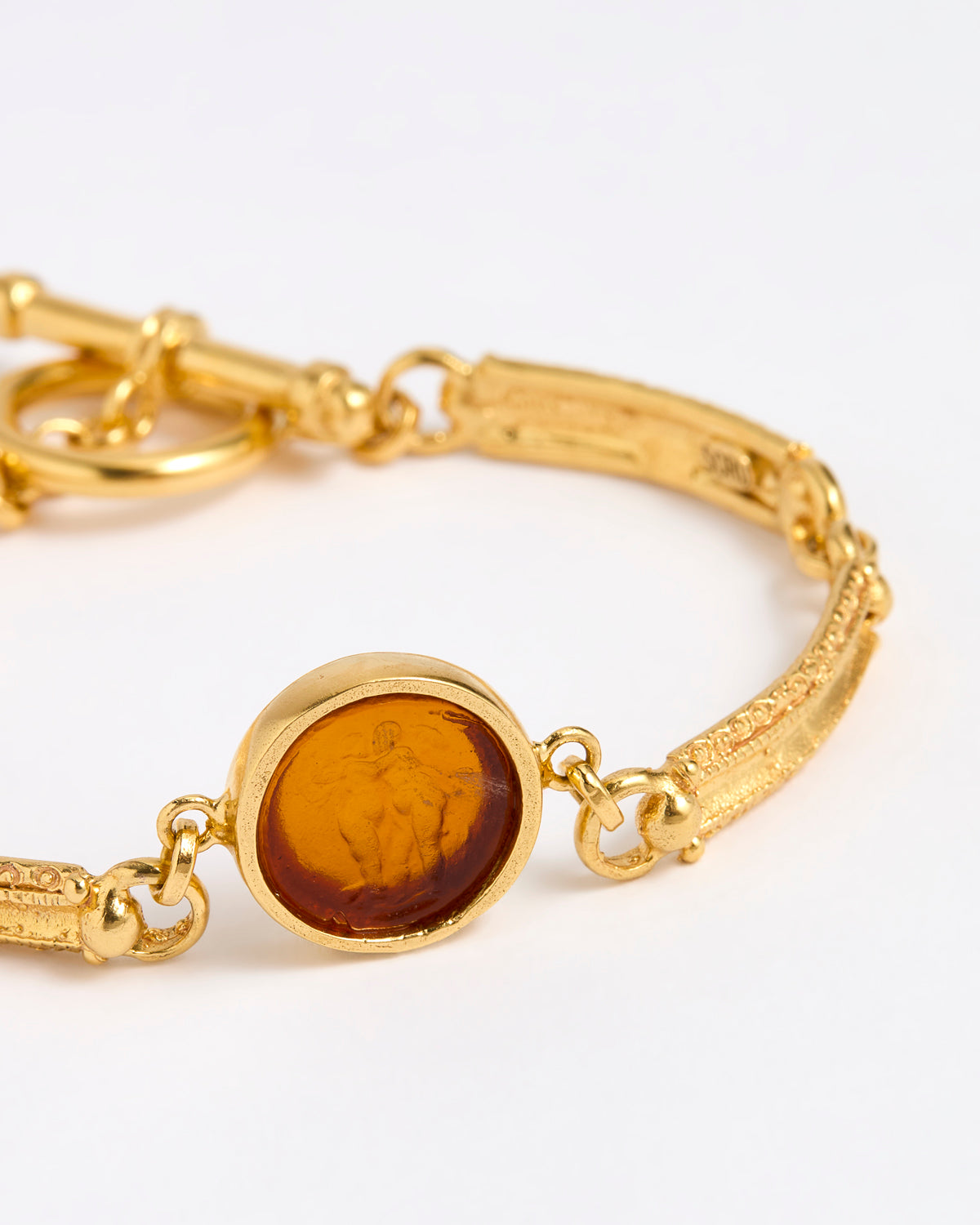 Close up of Gold link bracelet with round pendant in the centre with topaz glass