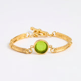 Gold link bracelet with round pendant in the centre with green glass 