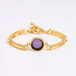 Gold link bracelet with round pendant in the centre with violet glass