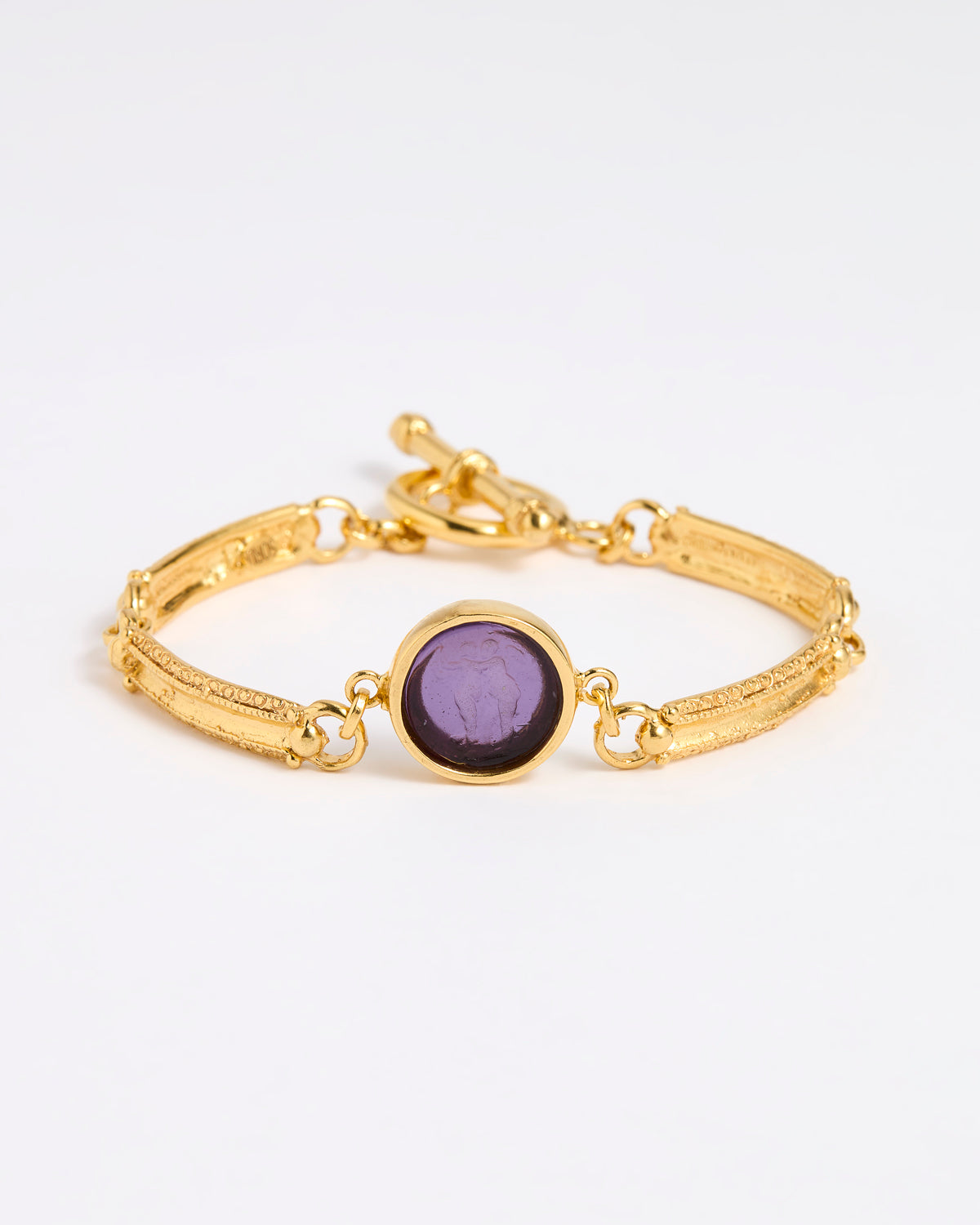 Gold link bracelet with round pendant in the centre with violet glass