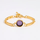 Gold link bracelet with round pendant in the centre with violet glass