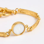 Close up of Gold link bracelet with round pendant in the centre with white glass