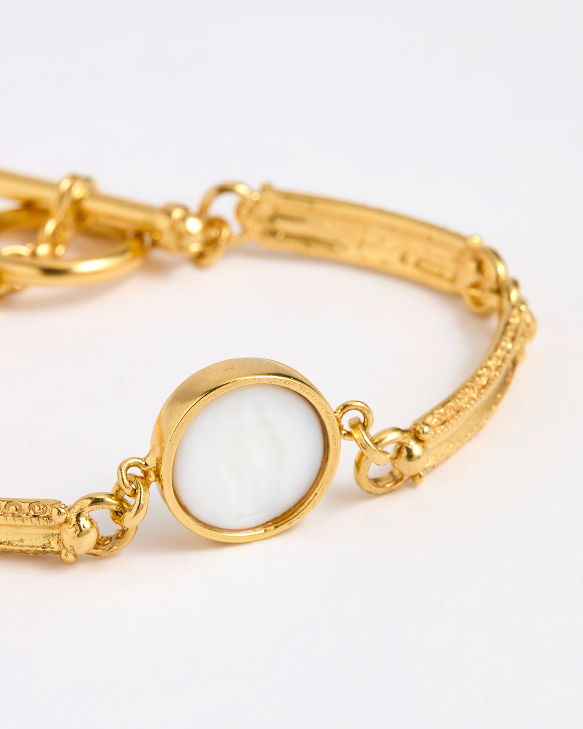 Close up of Gold link bracelet with round pendant in the centre with white glass