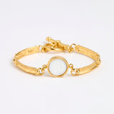 Gold link bracelet with round pendant in the centre with white glass