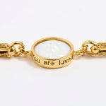 Gold link bracelet with round pendant in the centre with white glass and inscription 'you are loved' 