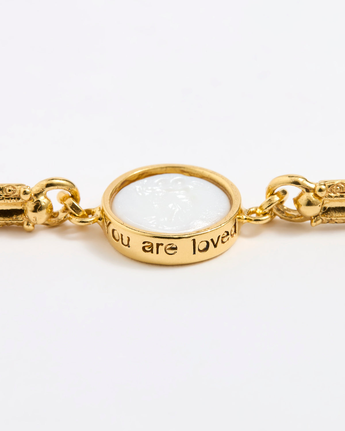 Gold link bracelet with round pendant in the centre with white glass and inscription 'you are loved' 