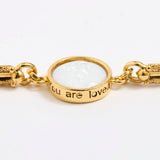 Gold link bracelet with round pendant in the centre with white glass and inscription 'you are loved' 