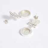 Reverse image of Silver drop earrings with round clear glass pendant featuring an image of twins.