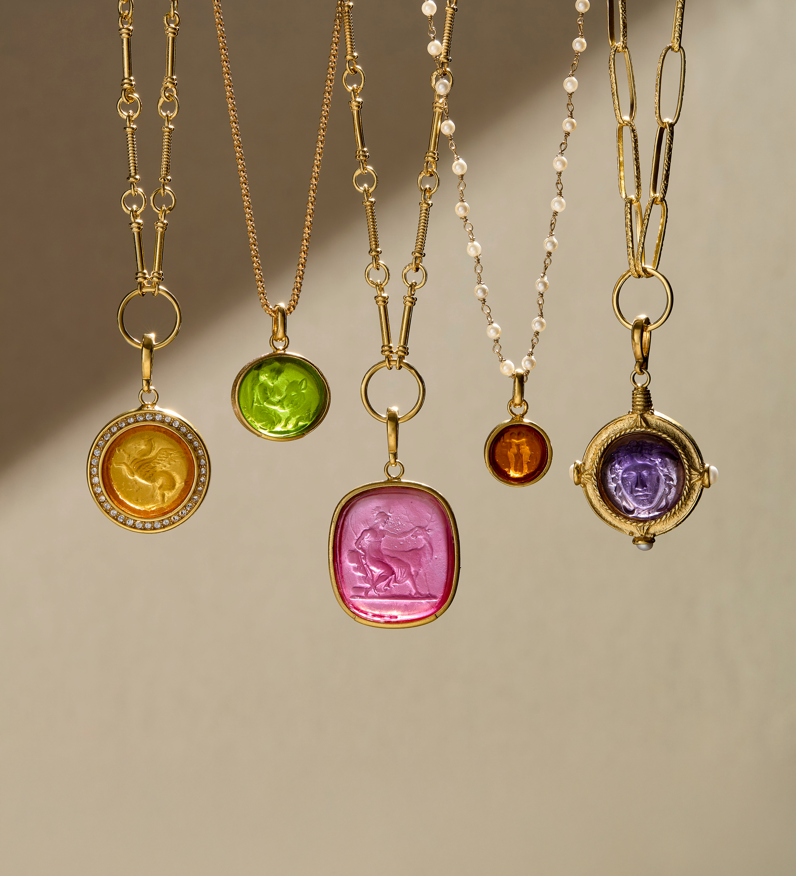 Set of gold necklaces with colorful gemstone pendants on a neutral background