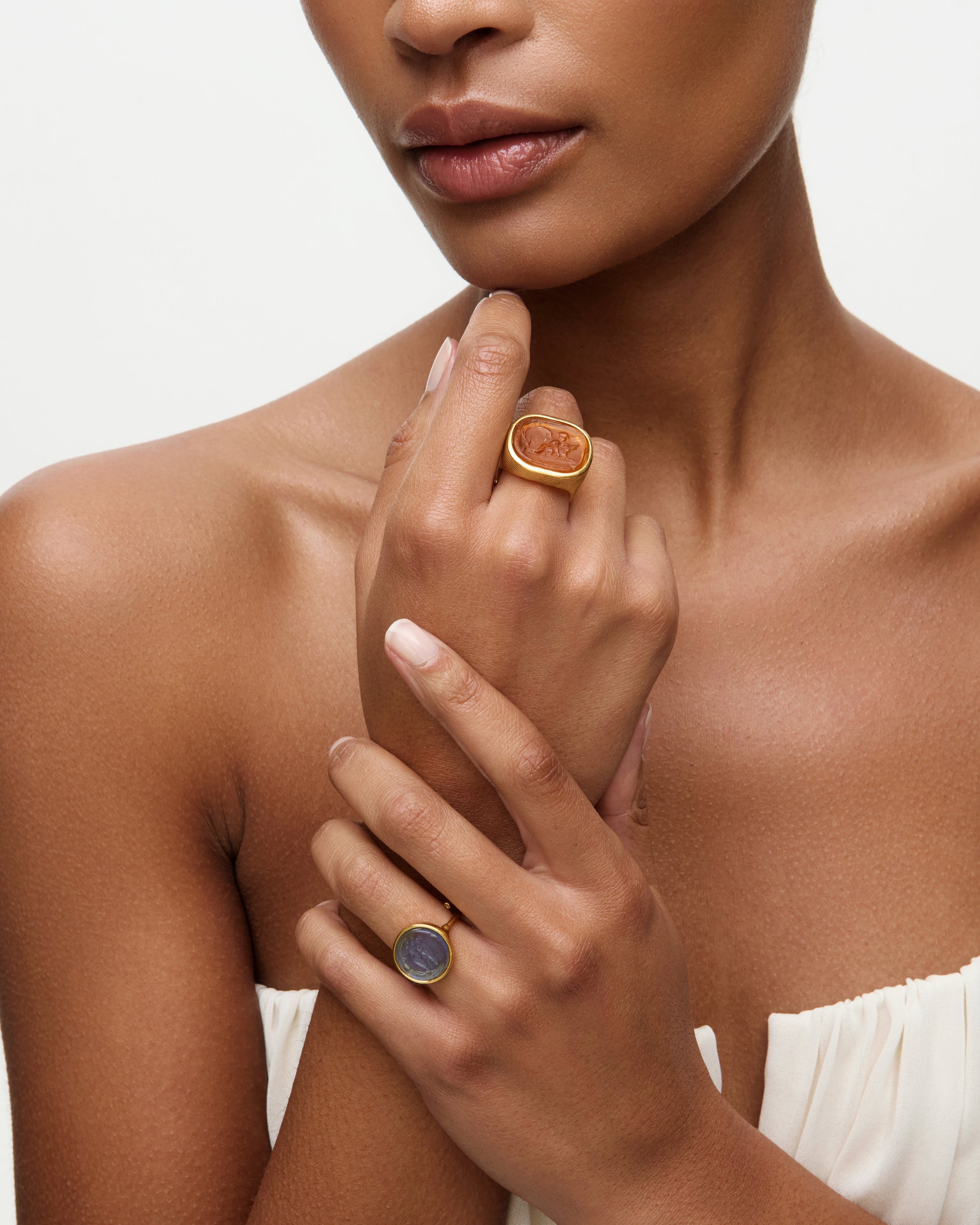 Woman wearing two rings on her fingers against a neutral background
