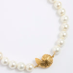 Pearl necklace with a gold coloured shell shaped pendant on a white background