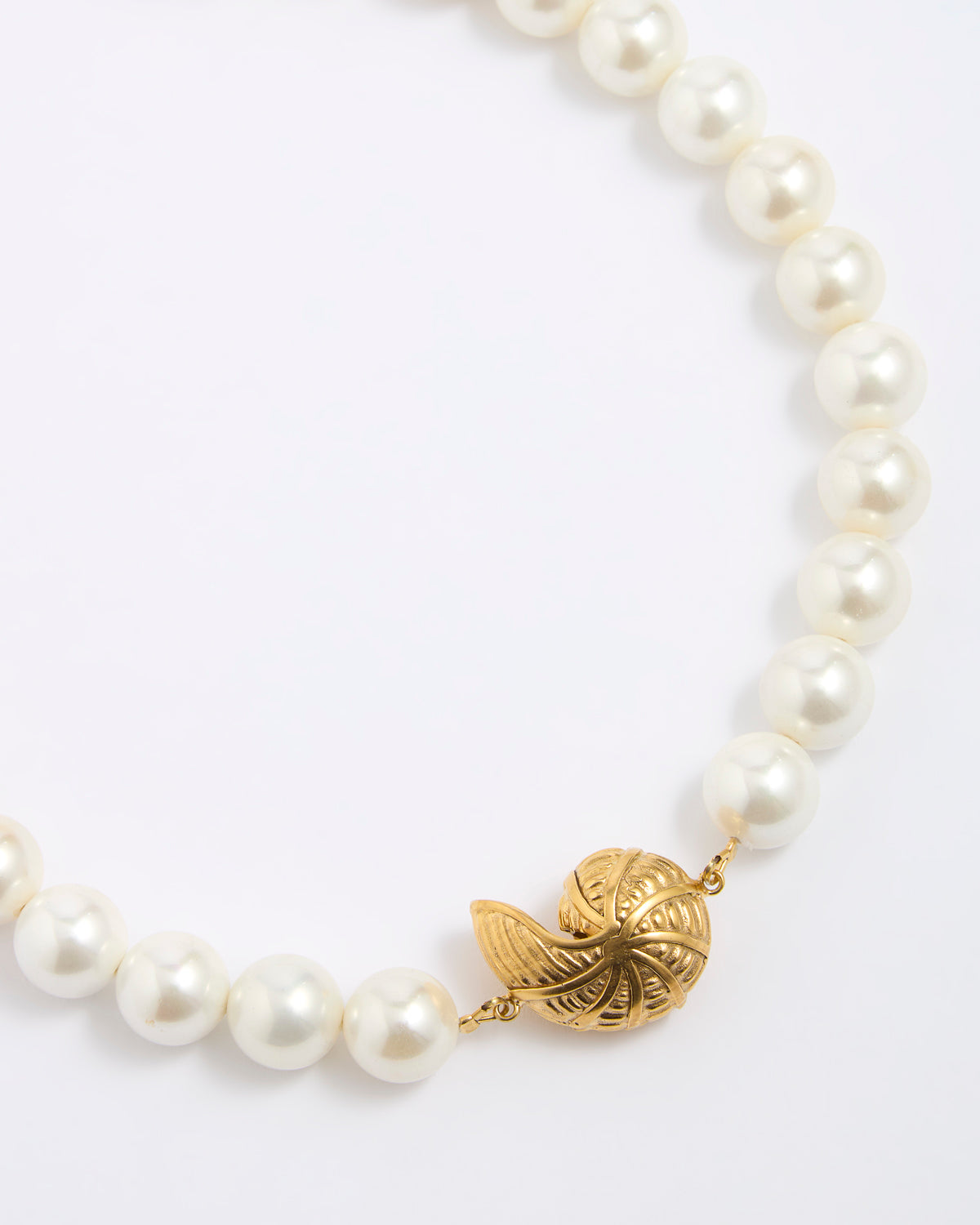 Pearl necklace with a gold coloured shell shaped pendant on a white background