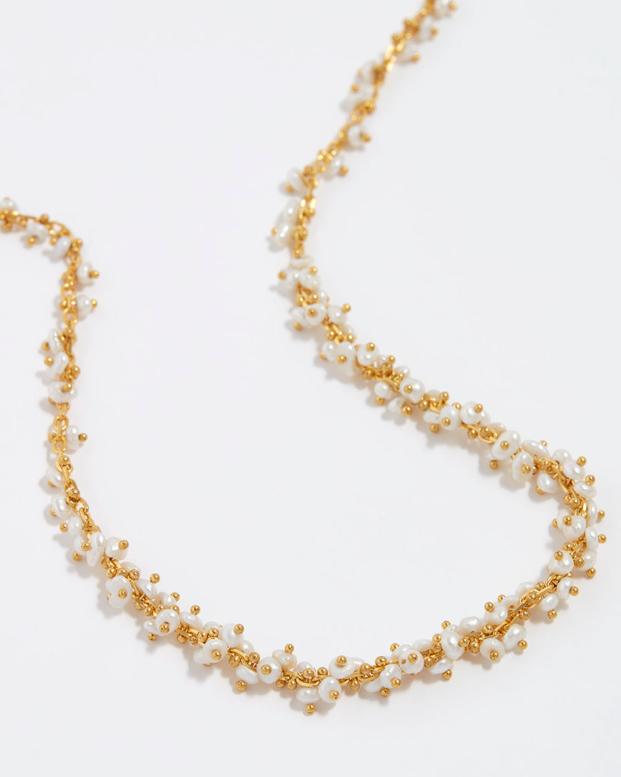 close up of gold necklace with pearl intertwined