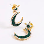 A pair of gold crescent moon and star earrings embellished with dark green and white opal crystals, displayed on a white background.