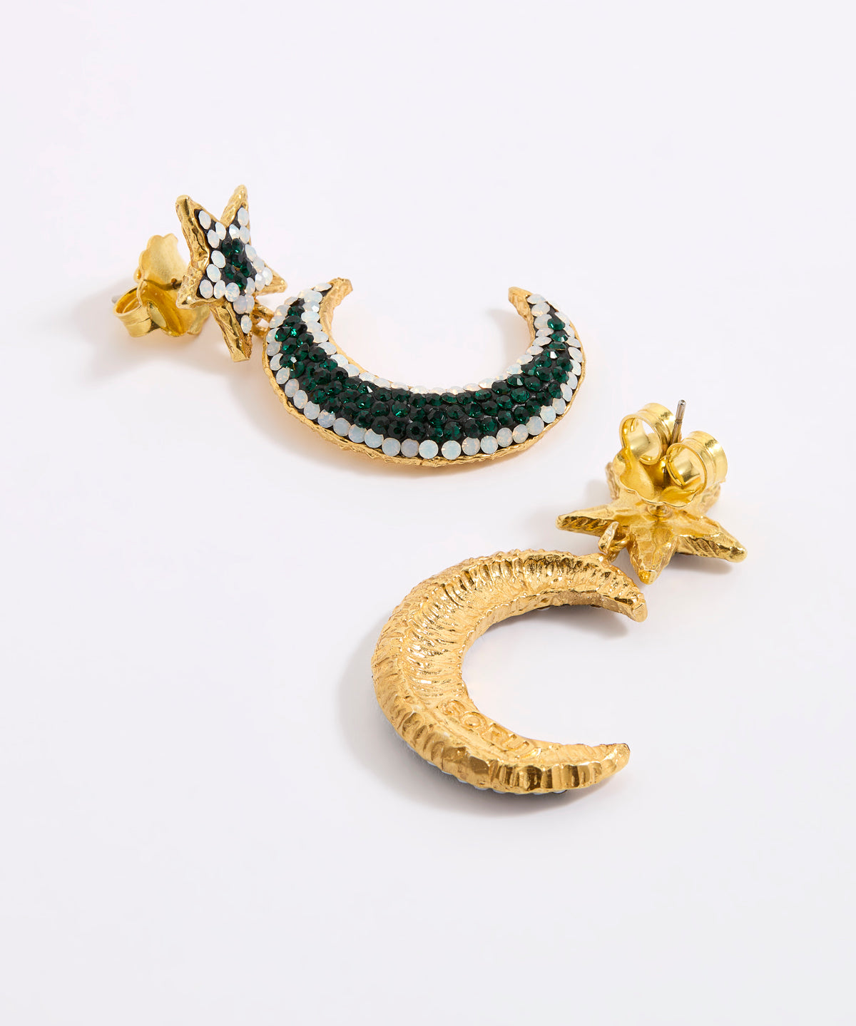 A pair of gold crescent moon and star earrings displayed against a white background. One earring is shown from the reverse, revealing a textured gold crescent moon, while the other features a gold crescent moon embellished with dark green and white opal rhinestones, complemented by a gold starburst post.
