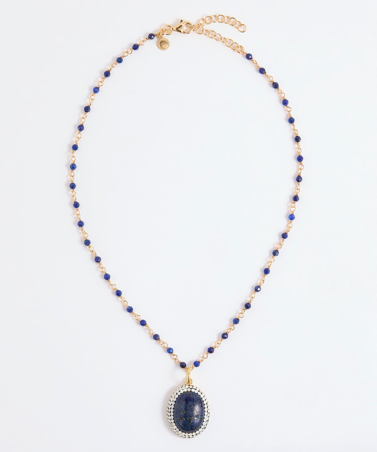 A beaded necklace featuring deep blue lapis lazuli stones and gold-toned spacer beads, with a large oval lapis lazuli pendant encircled by small white stones, displayed on a clean white background.