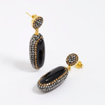 Pair of earrings with black and gold design on a white background