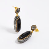 Pair of earrings with black and gold design on a white background