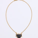 A gold chain necklace with a central triangular black stone pendant, accented with small clear stones around the pendant, shown on a plain white background.