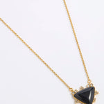 A gold chain necklace featuring a triangular black onyx pendant with small clear crystal accents in a gold setting, displayed on a white background.