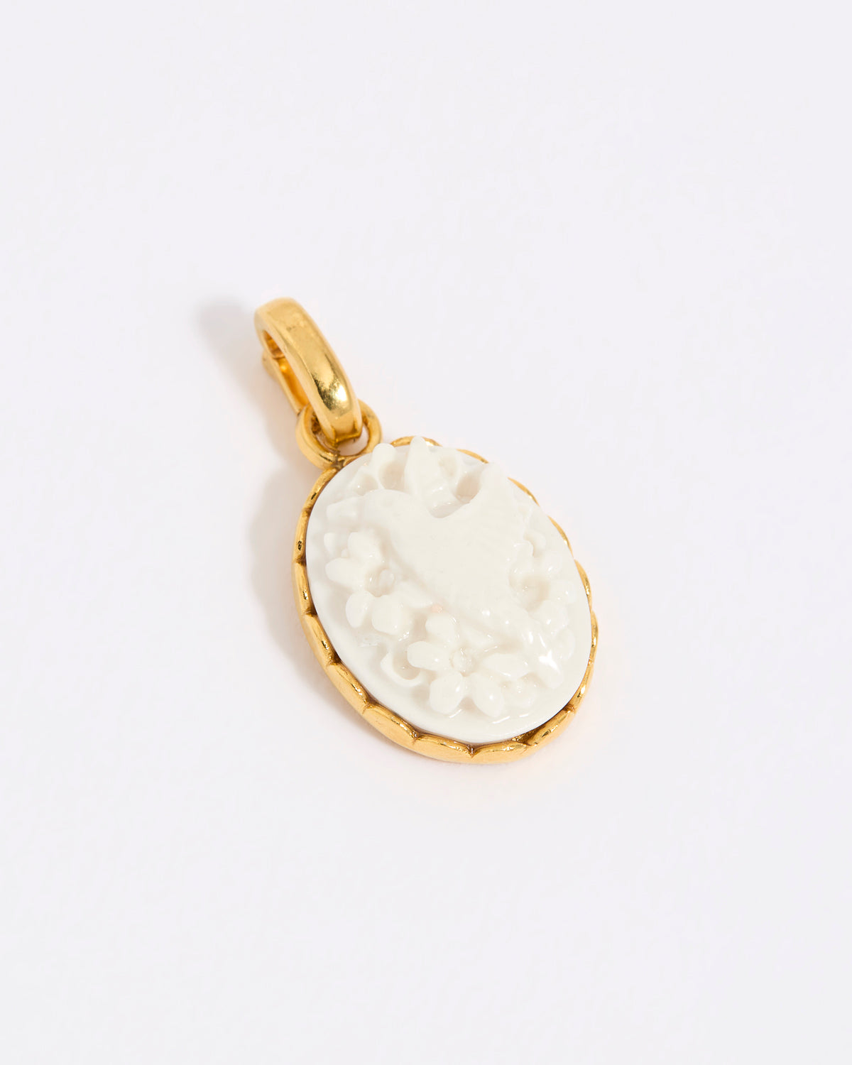 Gold coloured pendant with a white engraved design of a hummingbird on a light grey background