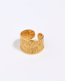 Close-up product shot of gold plated chunky band ring detailed filigree on a white background