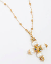 A close-up product shot of a large gold and pearl cross pendant hanging from a gold beaded necklace. The cross features pastel-colored agate gemstones, pearls, and detailed filigree work. The pendant is suspended from a textured beaded chain set against a white background.