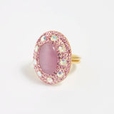 Close up product shot of adjustable ring  with pink centre stone surrounded by crystals on a white background