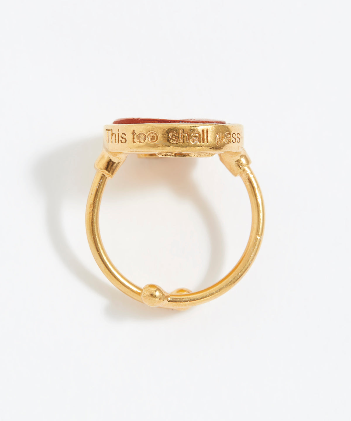 Gold ring with 'This too shall pass' engraving on a white background