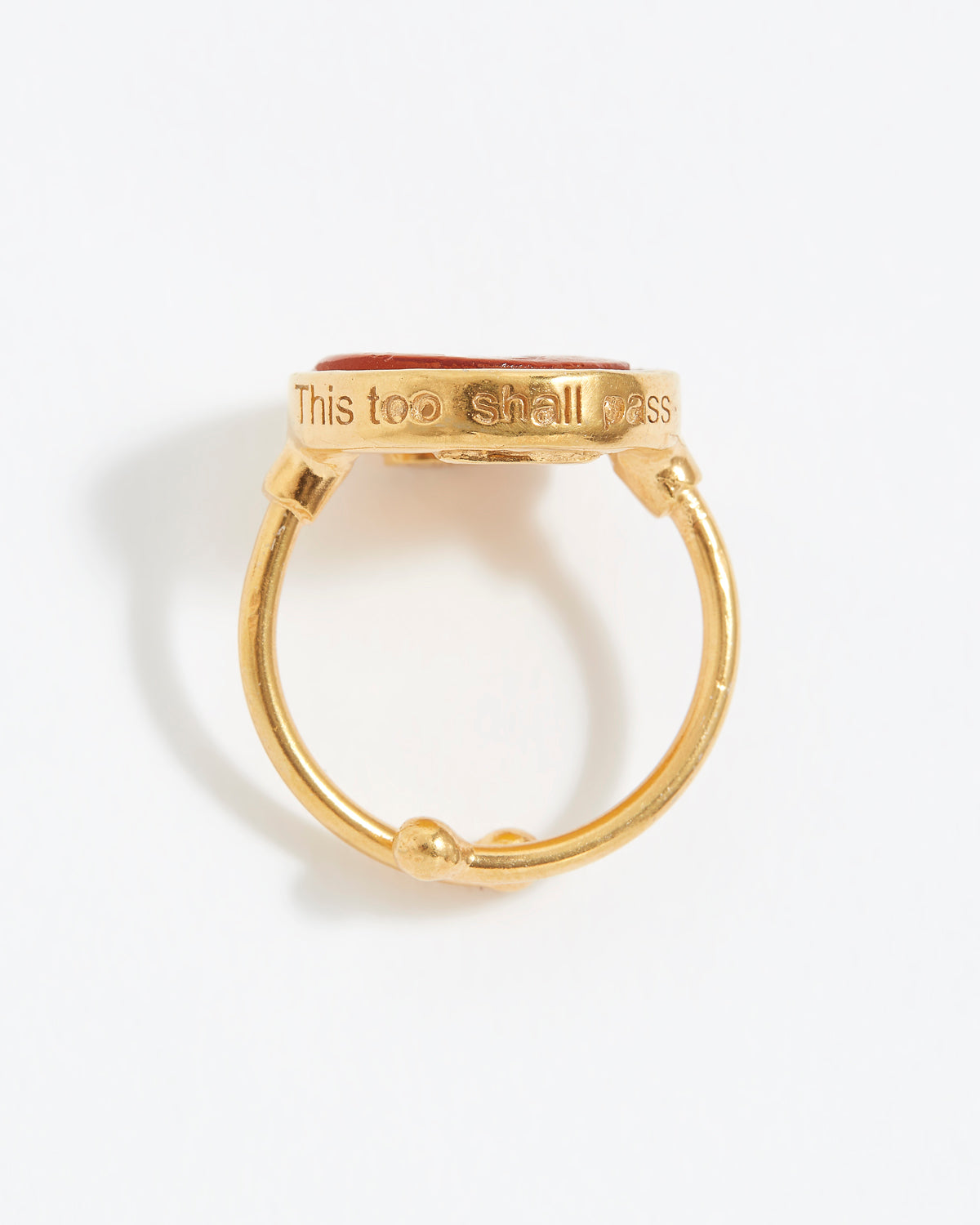 Gold ring with 'This too shall pass' engraving on a white background