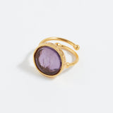 Gold ring with a purple gemstone on a white background