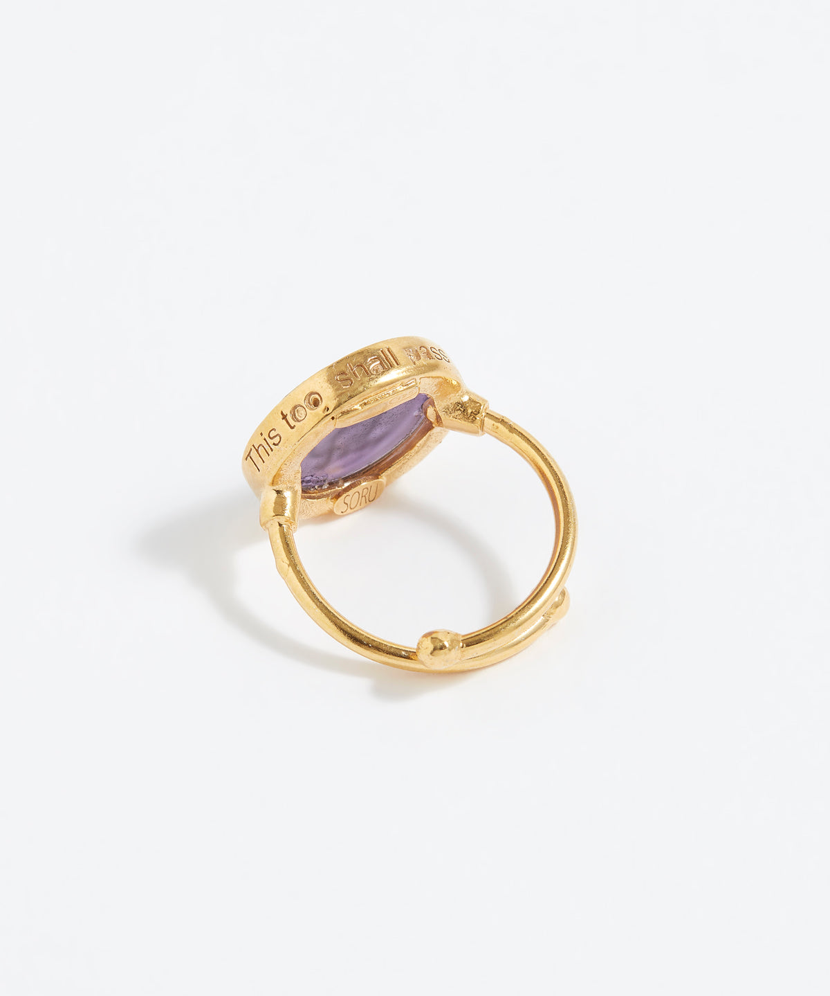 Gold ring with a purple stone on a white background