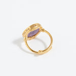 Gold ring with a purple stone on a white background