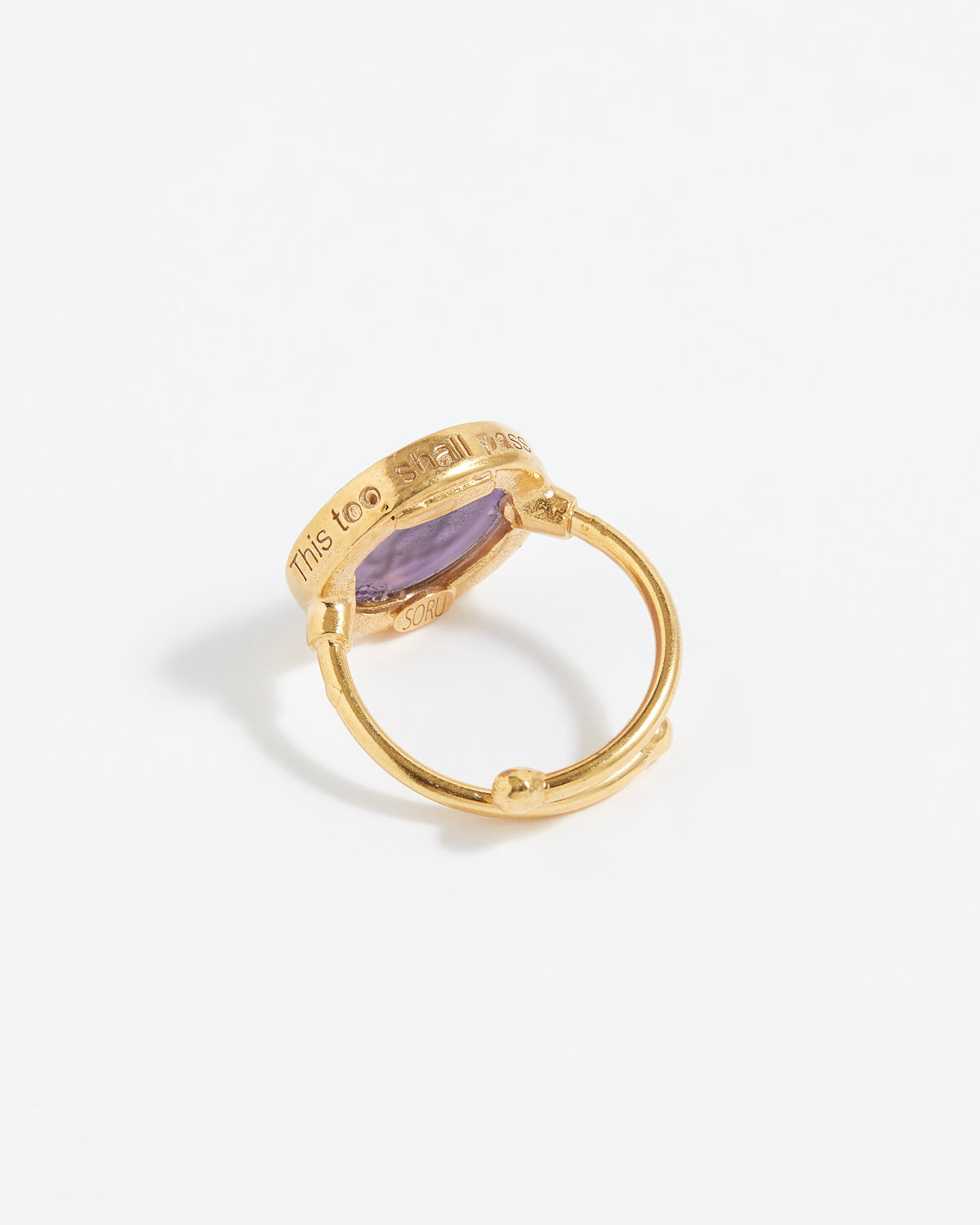 Gold ring with a purple stone on a white background