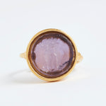 Gold ring with a purple stone on a white background