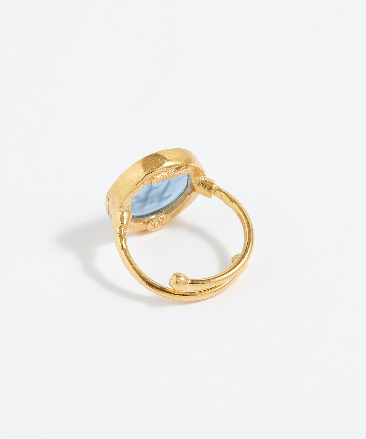 Gold ring with a blue stone on a light gray background