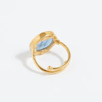 Gold ring with a blue stone on a light gray background