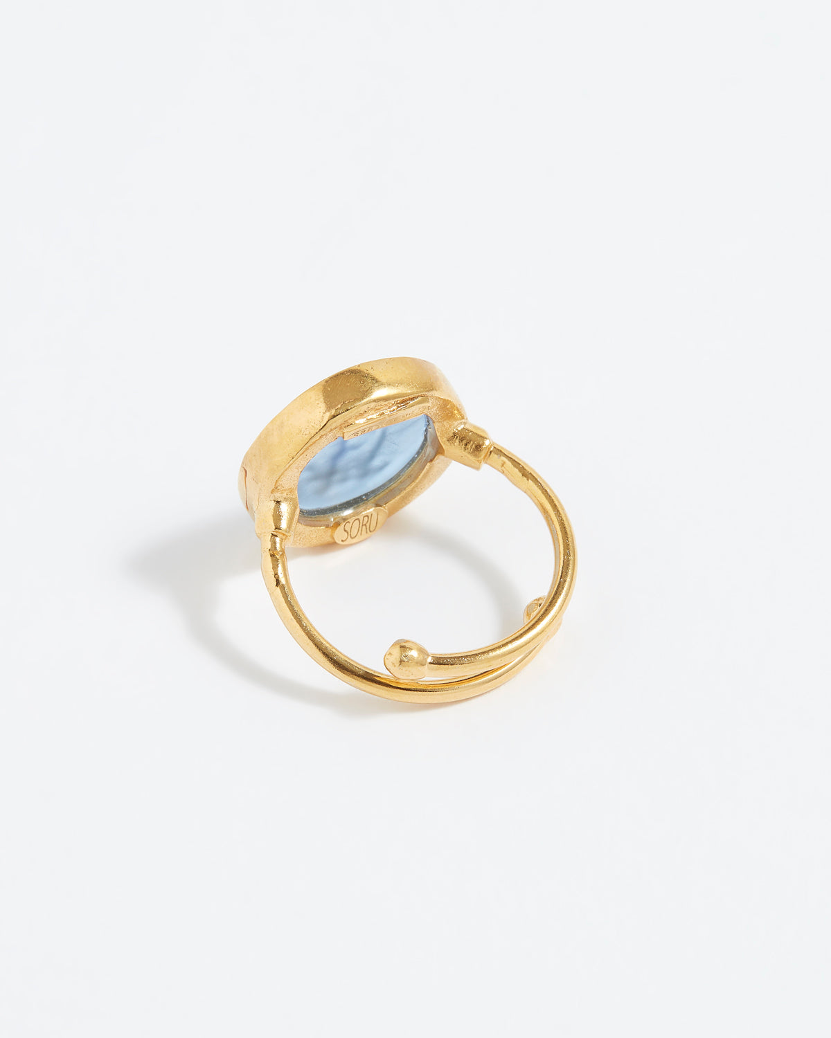 Gold ring with a blue stone on a light gray background