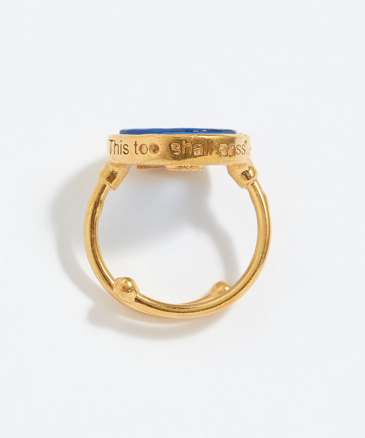Gold ring with blue stone with "This Too Shall Pass" engraved on a white background