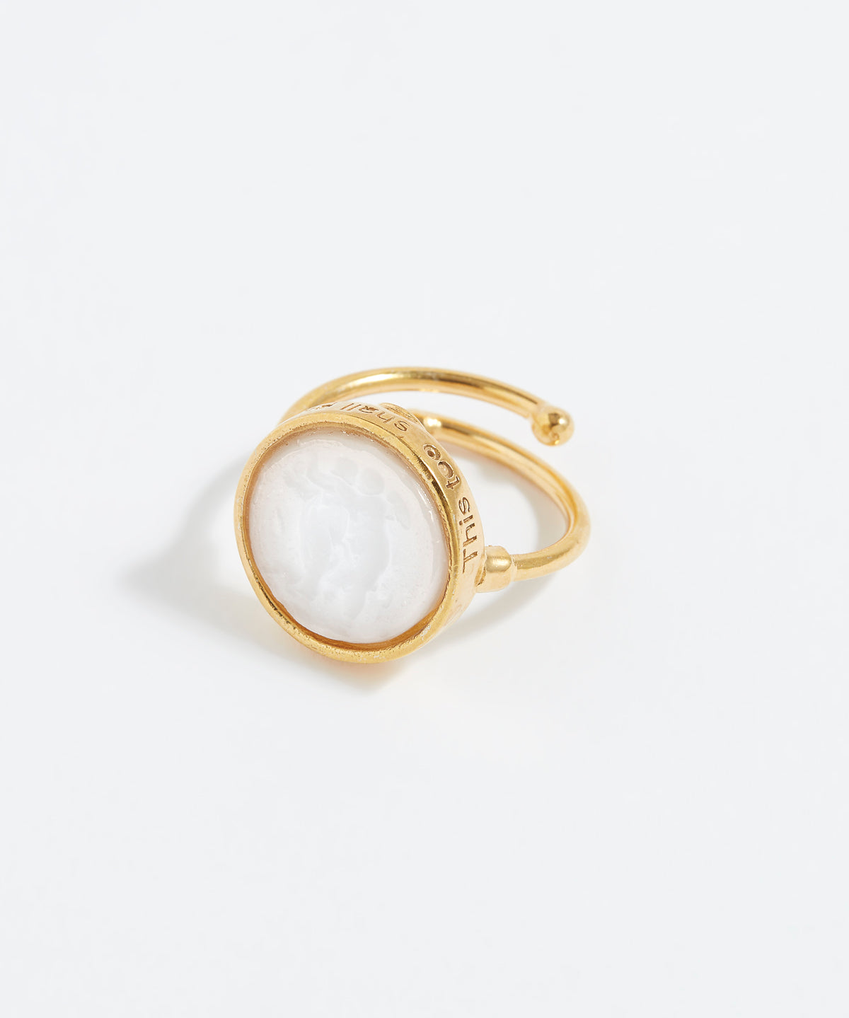 Gold ring with a white gemstone on a light gray background