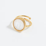 Gold ring with a white gemstone on a light gray background