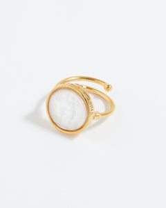 Gold ring with a white gemstone on a light gray background
