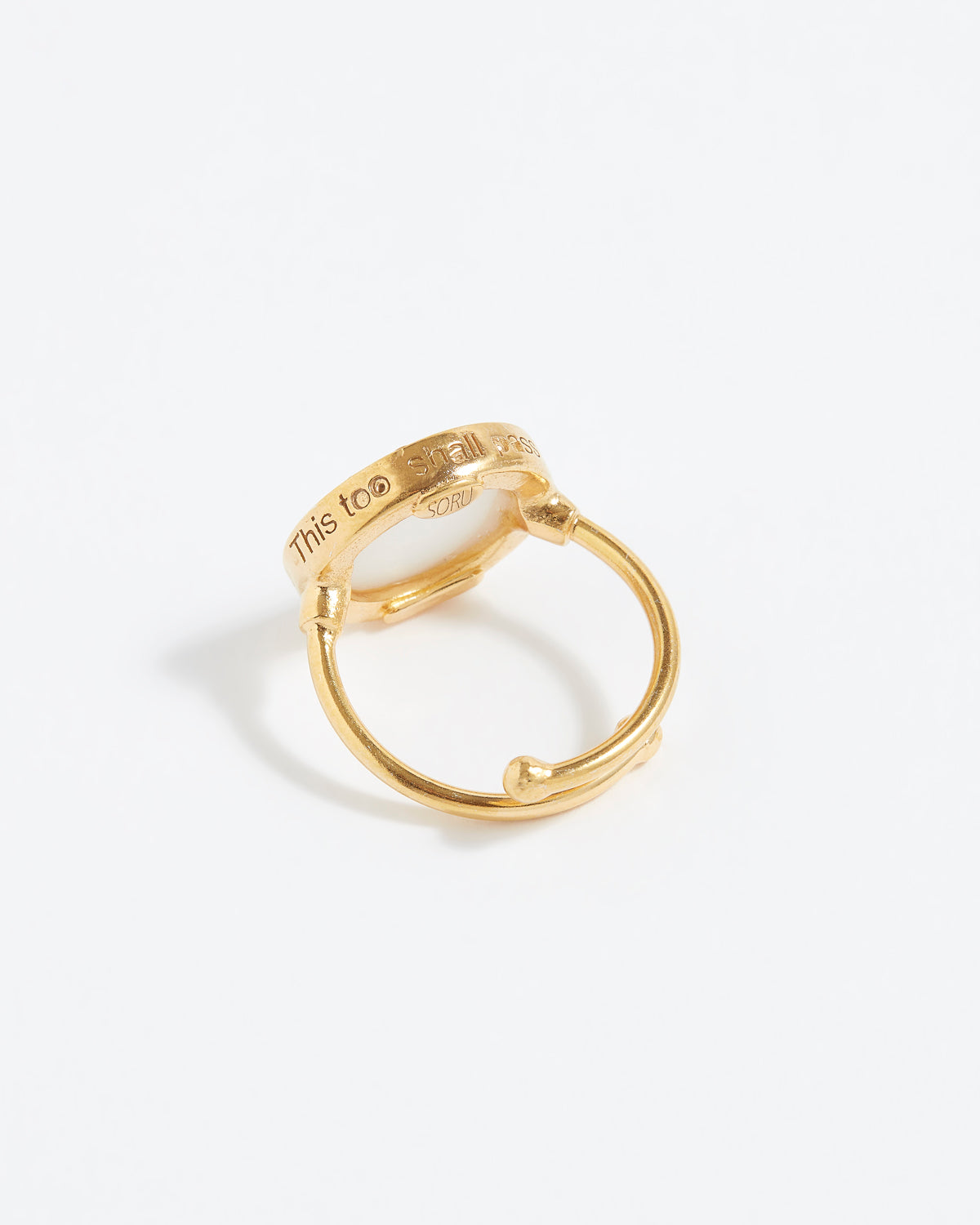 Gold ring with engraved text "This Too Shall Pass" on a white background