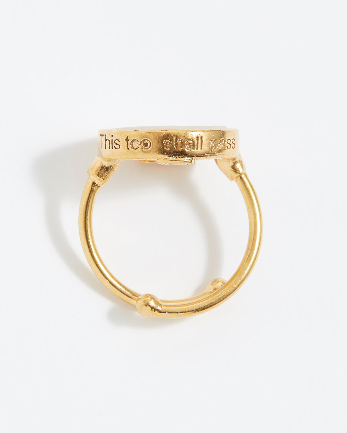 Gold ring with 'This too shall pass' engraving on a white background